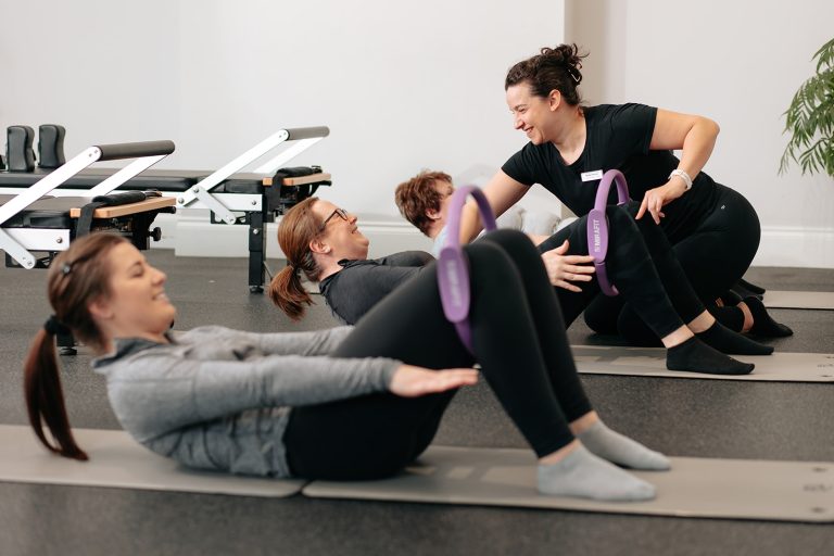 A combined mat work and Reformer Pilates class being taught by a Pilates instructor